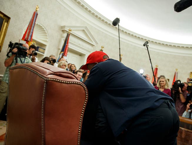 Trump für einmal ganz klein und kaum zu sehen: Der Rapper Kanye West sprang während eines Fototermins im Oval Office auf und umarmte den US-Präsidenten. (Bild: KEYSTONE/AP/EVAN VUCCI)