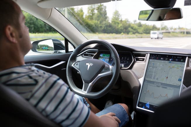 Ein Autofahrer faehrt mit Hilfe des Autopilotsystems eines Teslas. (Symbolbild: Gaetan Bally/Key)