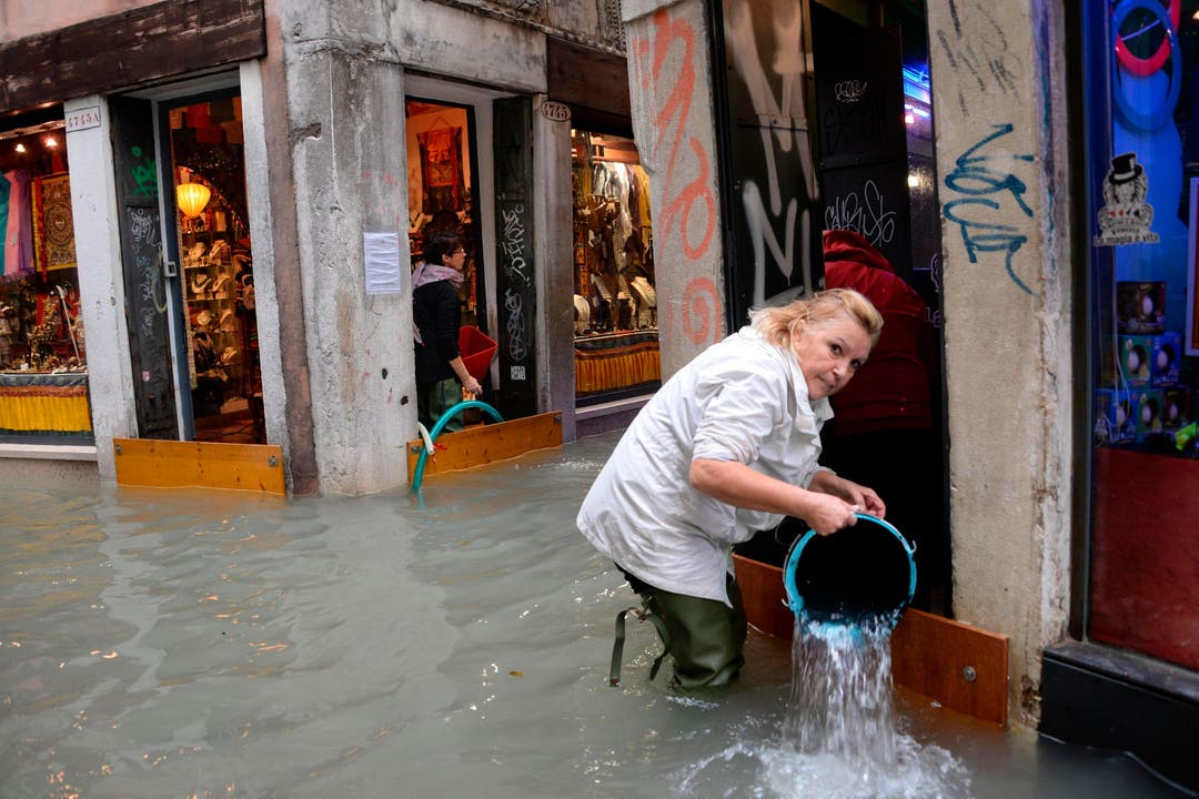Diese Frau schöpft Wasser aus einem überfluteten Laden. (Bild: Andrea Merola/Keystone (29. Oktober 2018))