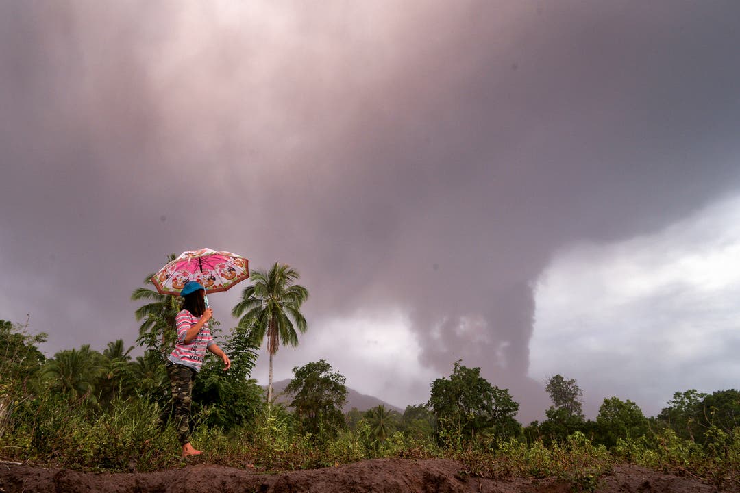 Eine Bewohnerin der Insel Sulawesi spaziert am aschespeienden Vulkan Soputan vorbei. (Bild: EPA/UNGKE PEPOTOH)