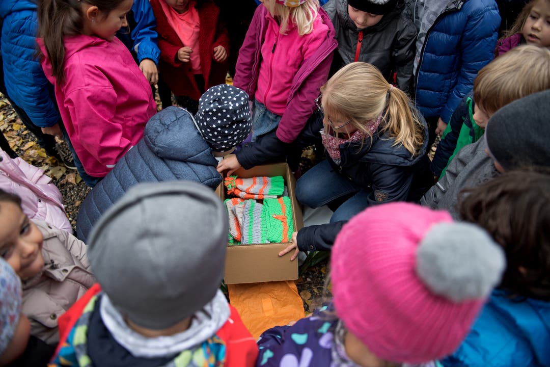Die Kinder scharen sich um das Paket mit den Mützen und können es kaum erwarten. Bild: Corinne Glanzmann (Sarnen, 30. Oktober 2018)