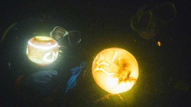 Zwei Taucher beleuchten mit ihren Lampen in dunkler Tiefe des Untersee ihre geschnitzten Rüben. (Bild: PD/Sandra Büchi)