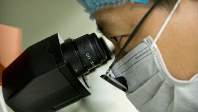 In this Oct. 9, 2018 photo, Qin Jinzhou looks through the lenses of a microscope as he works at a laboratory in Shenzhen in southern China's Guangdong province. Chinese scientist He Jiankui claims he helped make world's first genetically edited babies: twin girls whose DNA he said he altered. He revealed it Monday, Nov. 26, in Hong Kong to one of the organizers of an international conference on gene editing. Qin is an embryologist in He's lab. (AP Photo/Mark Schiefelbein)