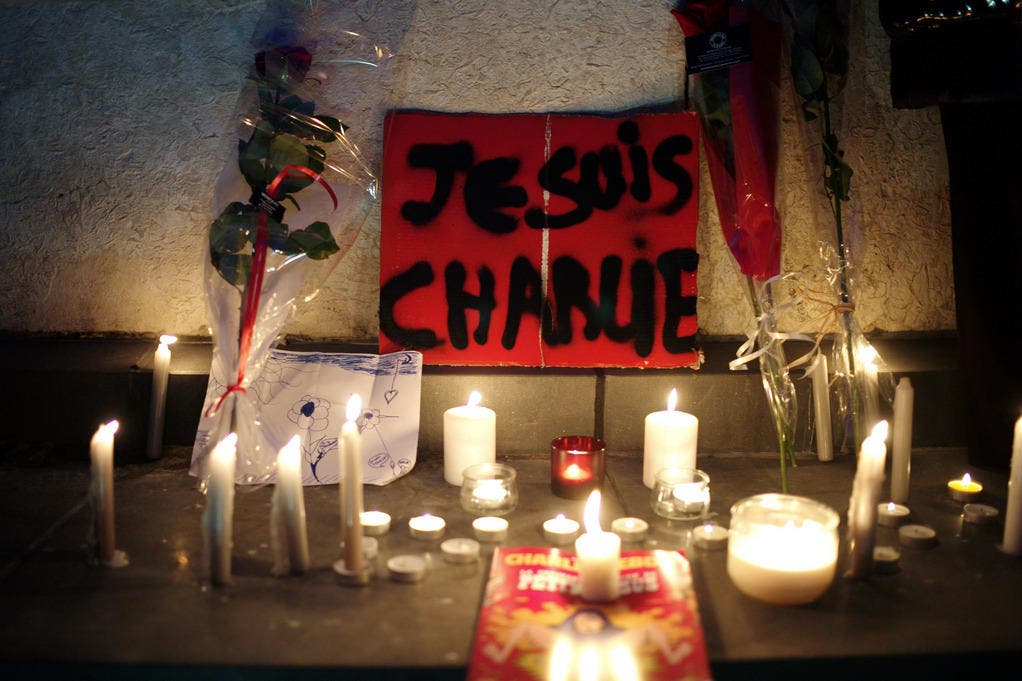 Nach der Attacke auf die Redaktion des Satiremagazins "Charlie Hebdo" haben Menschen in Gedenken an die Opfer ein Plakat mit der Aufschrift "Je suis Charlie" sowie Kerzen aufgestellt in Paris. (Bild: Keystone)