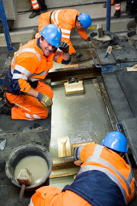 Arbeiter reiben mit einem goldigen Brett die Beton Schicht im längsten Eisenbahntunnel der Welt glatt. (Bild: SIGI TISCHLER)