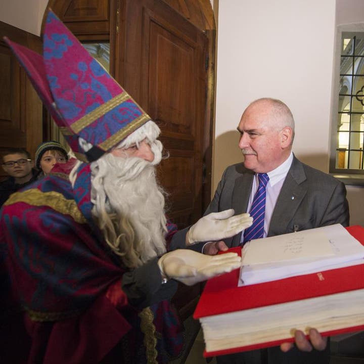 Der Luzerner Kantonsratspräsident Urs Dickerhof erhält vom Samichlaus ein grosses Buch mit dem Titel «AUS BILD UNG» (Bild: Keystone)