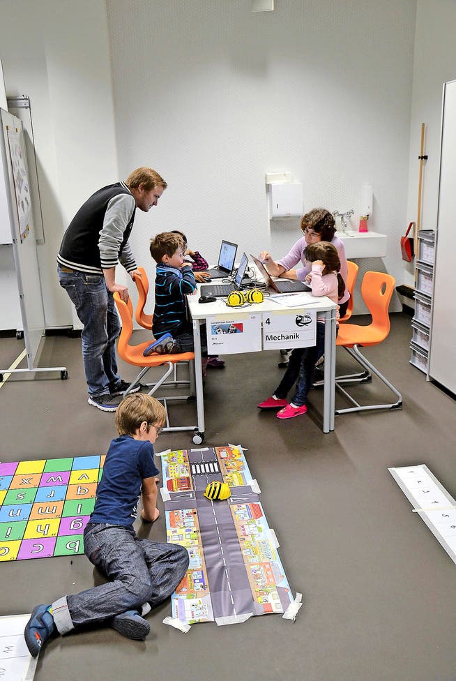 Spielerisch werden Erstklässler vom Schulhaus Maihof an der Pädagogischen Hochschule Luzern in die Robotik eingeführt. Mittel dazu sind Lego-Autos (rechts oben), Tablet-Computer (Mitte) oder eine Roboterbiene (unten). (Bilder Beatrice Vogel/PD)