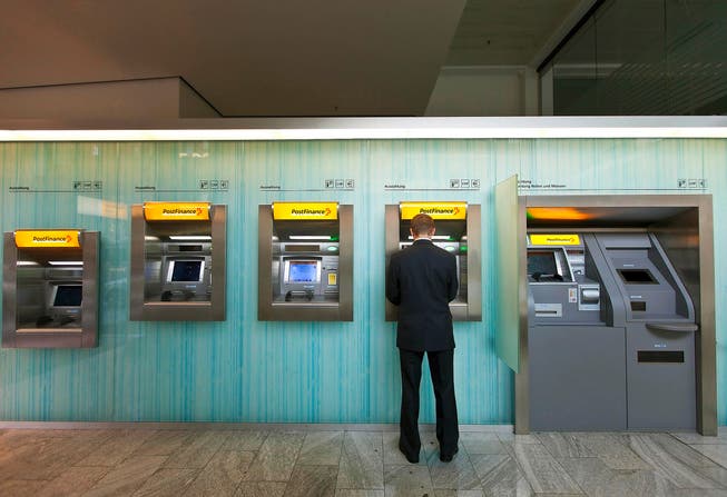 Ein Mann bezieht Geld vom Postomaten. Postfinance besitzt sehr viele Kunden, die in den USA steuerpflichtig sind. (Bild: Keystone/Gaetan Bally)