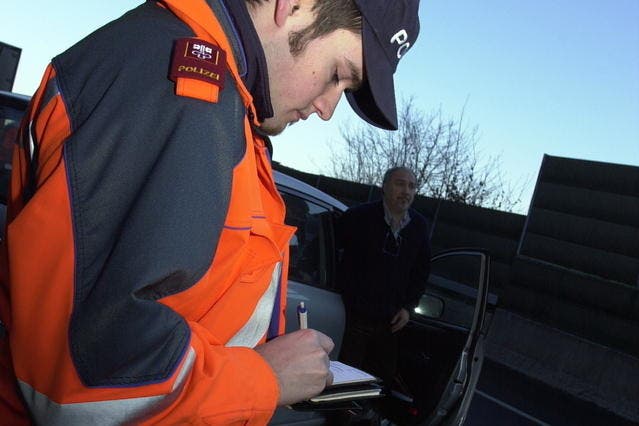 Ein Polizist schreibt am Lopper einen Bussenzettel. (Archivbild Fabian Fellmann/Neue NZ)