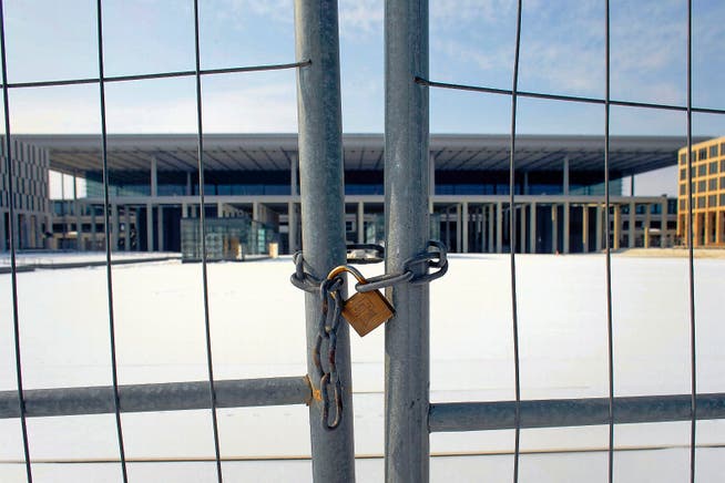 Noch immer kann der neue Berliner Flughafen nicht genutzt werden. Blick durch den mit einer Kette gesicherten Bauzaun auf den Hauptterminal. (Bild: AP/Markus Schreiber)