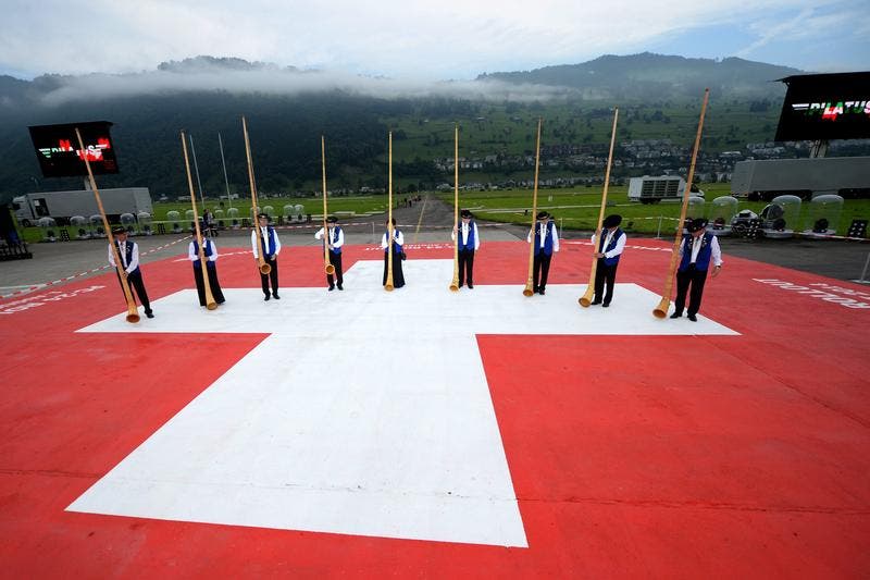Die Ruhe vor der Enthüllung: Alphornbläser positionieren sich auf einer riesigen Schweizer Flagge für ihren Auftritt. (Bild: Keystone)