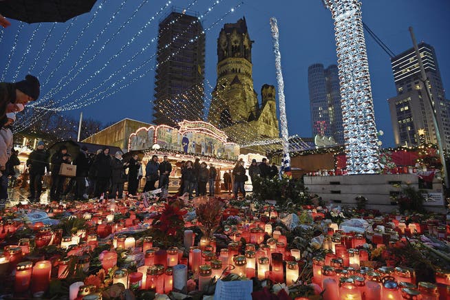 Zahlreiche Menschen stehen um Blumen und Kerzen, die am Weihnachtsmarkt am Breitscheidplatz in Berlin abgelegt wurden. (Bild: Rainer Jensen/Keystone (Berlin, 22. Dezember 2016))
