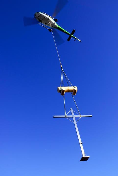 Das Kreuz kommt mit einem Helikopter samt Bänkli geflogen. (Bild: Erhard Gick / Neue SZ)