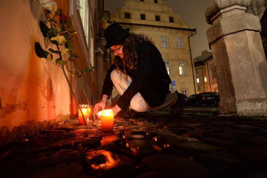 Ein Mann entzündet eine Kerze vor der französischen Botschaft in Prag. (Bild: Keystone)