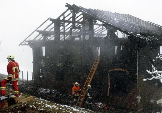Feuerwehrmänner inspizieren das Haus, welches in der vergangenen Nacht abgebrannt ist. (Bild: Keystone/Steffen Schmidt)