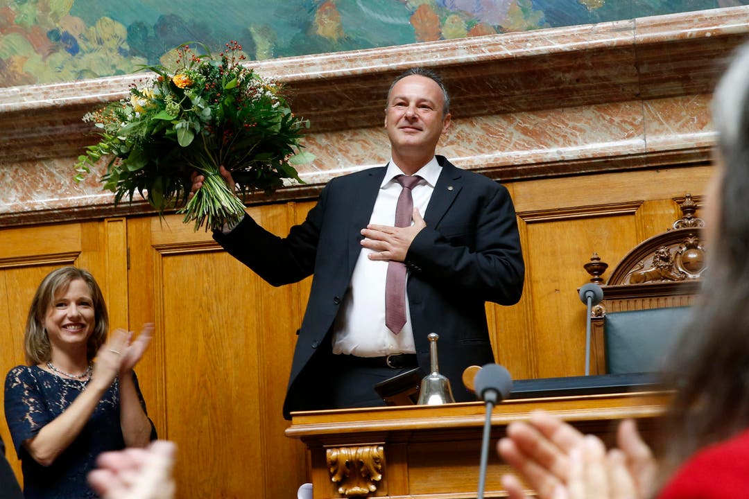 Nationalratspräsident Stephane Rossini erhält Blumen und Applaus im Nationalratssaal. (Bild: Peter Klaunzer / Keystone)