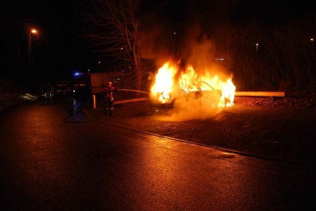 Ein Feuerwehrmann löscht das in Flammen stehende Auto. (Bild: Kantonspolizei Luzern)