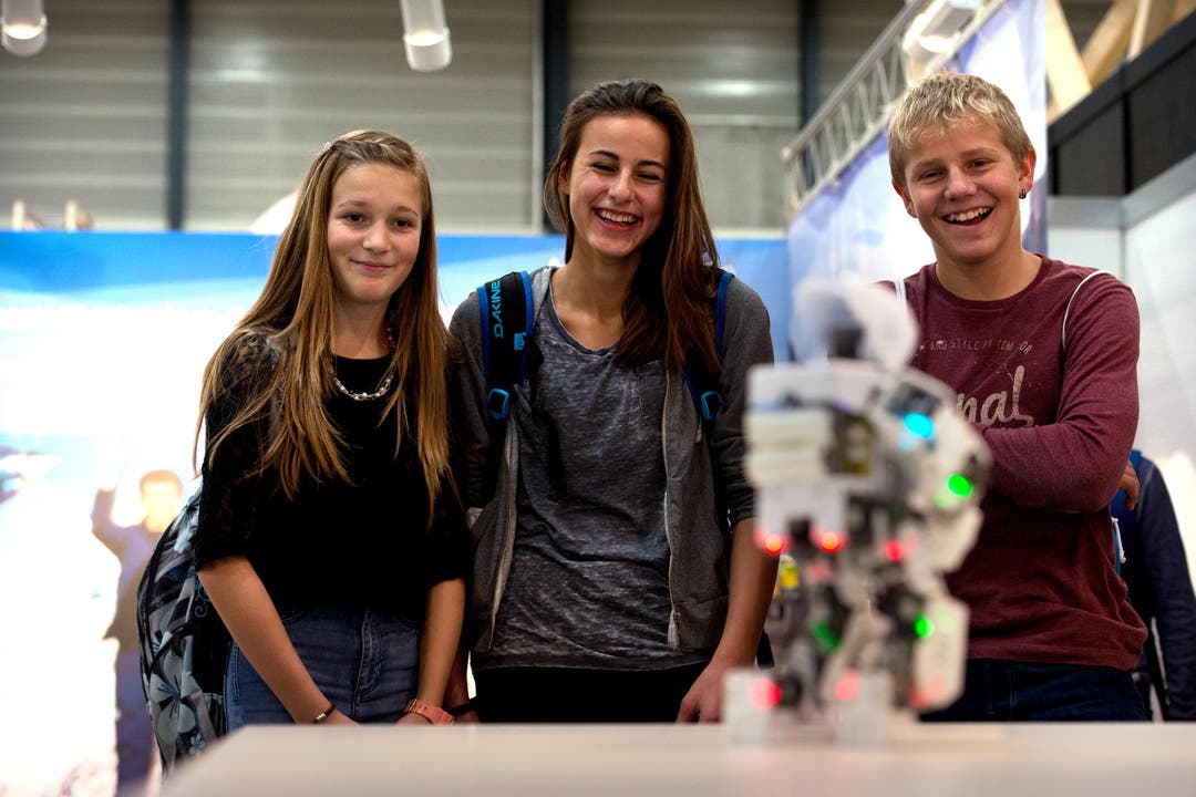 Luisa Pfyl, Julia Wigget und Oliver Schuler amüsieren sich an der Zentralschweizer Bildungsmesse Zebi auf der Luzerner Allmend an einem Roboter. (Bild: Nadia Schärli / Neue LZ)