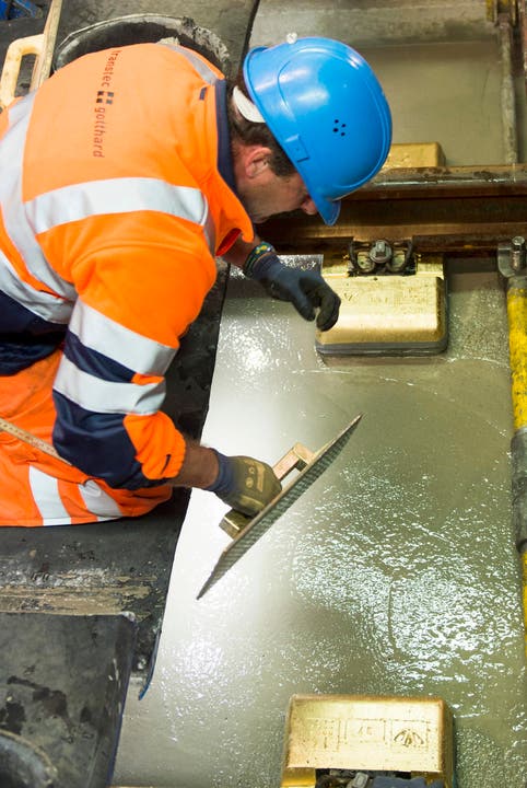 Arbeiter Helmut Fortschegger reibt mit einem goldigen Brett die Beton Schicht im längsten Eisenbahntunnel der Welt glatt. (Bild: SIGI TISCHLER)