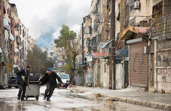 Rauchsäulen und bewaffnete Menschen zeugen von Kampfhandlungen im von Rebellen gehaltenen Teil von Aleppo.Bild: Karma Al-Masri/AFP (14. Dezember 2016)