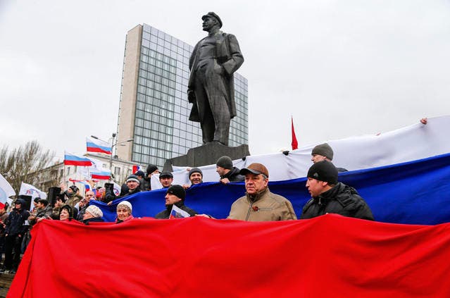 Pro-russische Demonstranten bilden eine Russkand-Fahne unter der Statue von Vladimir Lenin. (Bild: AP / Andrey Basevich)