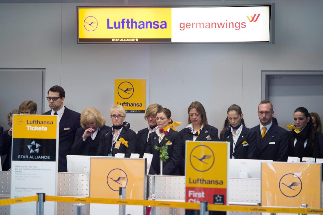 Mittwoch, 10.53 Uhr am Schalter der Lufthansa in Düsseldorf: Angestellte gedenken mit einer Schweigeminute der Opfer des Germanwings-Absturzes. (Bild: Keystone)