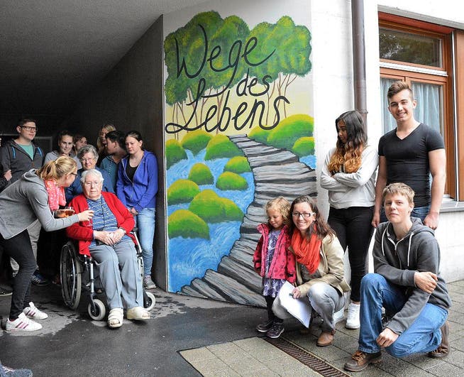 Schüler, Lehrer und Senioren beim Wandbild «Wege des Lebens». (Bild Romano Cuonz)