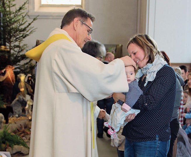 Pfarrer Thomas Meli segnet Leandra, gehalten von ihrer Mutter Antonia Enz. (Bild: Patricia Helfenstein-Burch (Alpnach, 28. Dezember 2017))