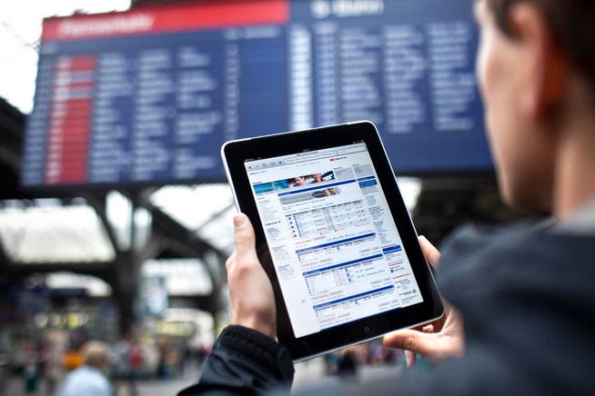 Ein Mann studiert auf einem iPad am Hauptbahnhof in Zürich den Fahrplan. (Symbolbild) (Bild: Keystone)