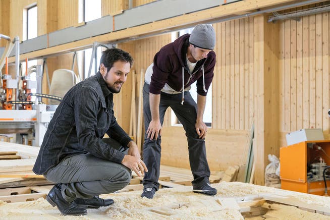 Projektleiter Krystian Grzybek (rechts) zeigt Daniel Albrecht in den Räumen der Holzbaufirma Walter Küng in Alpnach die einzelnen Arbeitsschritte zum fertigen Holzpur-Wandelement.Bild: PD