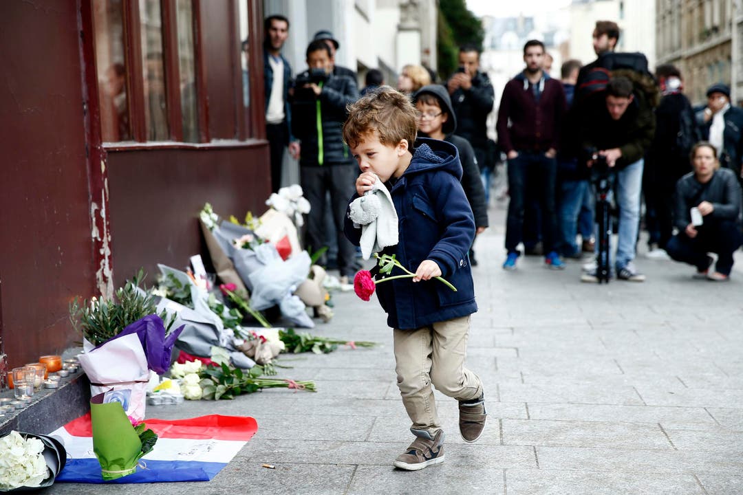 Ein kleiner Knabe legt vor dem Cafe Carillon in Paris Blumen nieder. (Bild: EPA/Yoan Valat)