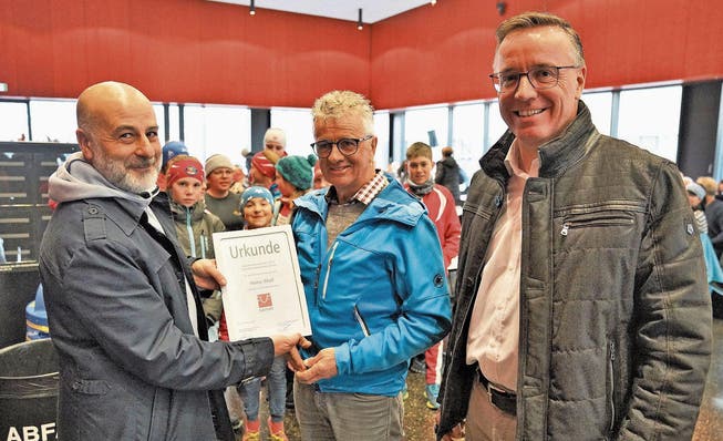Biathlontrainer Heinz Wolf (Mitte) erhält von Cleo Bracale (links) und Gemeindepräsident Jürg Berlinger den Sarner Sportförderungspreis. (Bild: Romano Cuonz (18. März 2018))