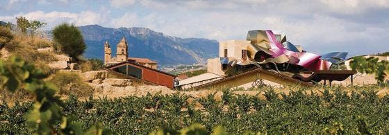 Wie eine vom Himmel gefallene Aluminiumrolle: Das extravagante Fünf-Sterne-Hotel des Weingutes Marques de Riscal, dahinter das mittelalterliche Städtchen Elciego. (Bilder: pd)