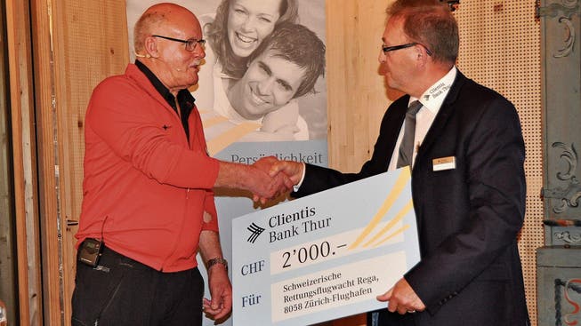 Jakob Frischknecht, Vorsitzender der Geschäftsleitung der Clientis Bank Thur (rechts), übergibt einen Check zu Gunsten der Rega an den Referenten Urs Bless. (Bild: Sabine Schmid)