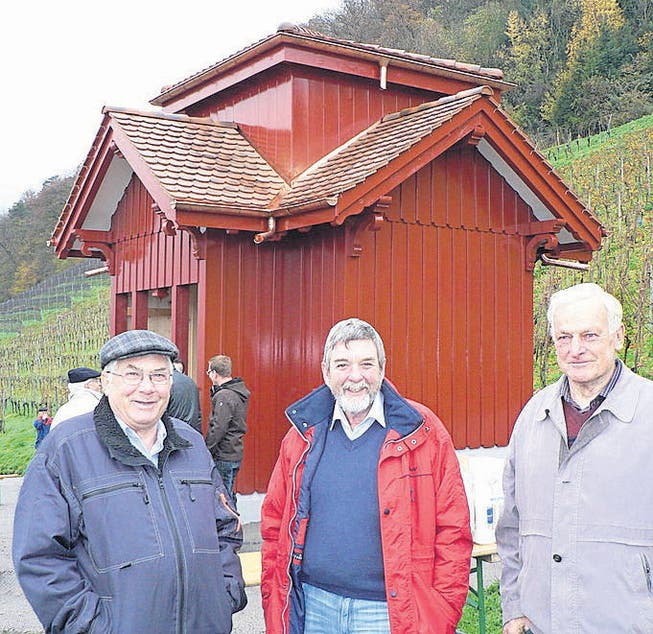 Die Rebbauern Bruno Zünd, Roland Coray und Jakob Ritz vor dem in neuem Glanz erstrahlenden roten Rebhüttli. (Bild: Ulrike Huber)