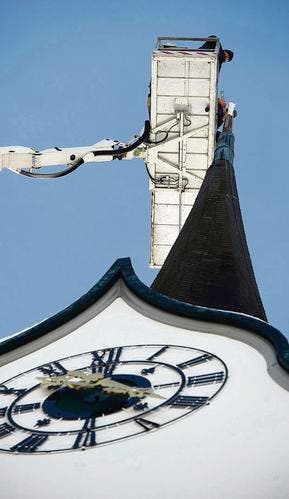 Eine Hebebühne hievt die frisch renovierte Kugel und das Kreuz auf die Turmspitze der Kirche St. Anna. (Bild: Ralph Ribi)