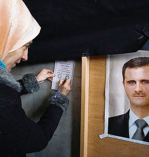 Syrische Stimmbürgerin neben einem Porträt Diktator Assads. (Bild: ap/Muzaffar Salman)