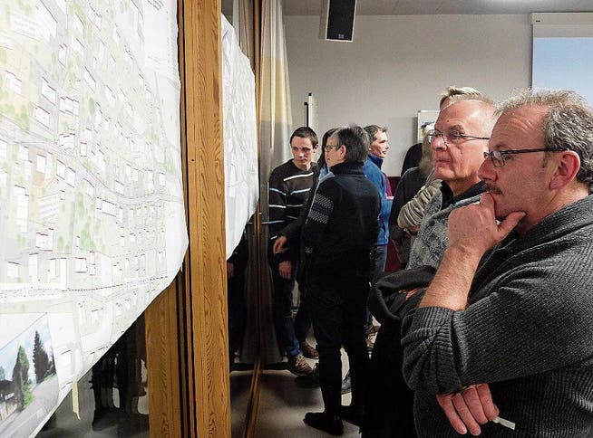 Teilnehmer des Info-Anlasses mustern die ausgehängten Pläne zur Umgestaltung der Dorfdurchfahrt. (Bild: Stefan Hilzinger)