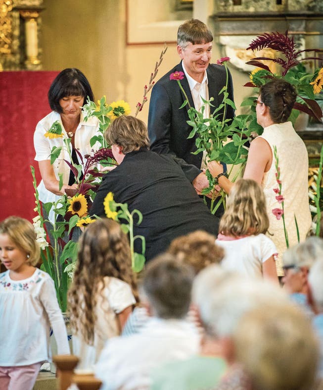 Die Gottesdienstbesucher verabschieden den Pfarrer und seine Frau mit Blumen. (Bild: Reto Martin)