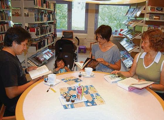 Gemütlichkeit am Zopfzmorge: Papa José und Mama Nadine lesen, während der kleine Lucio Meza Sanchez ein Stück Zopf mampft. Bibliothekarin Christine Gründler gefällt's. (Bild: ch)