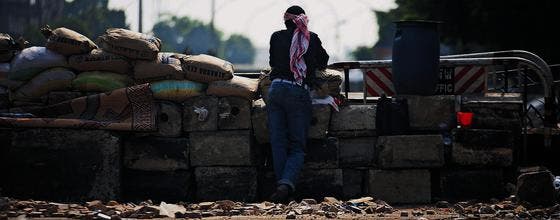 Ein Anhänger des gestürzten Präsidenten Mursi hinter einer Barrikade. Der anhaltende Konflikt mit den Islamisten erschwert in Ägypten die Bildung einer Übergangsregierung. (Bild: ap/Manu Brabo)