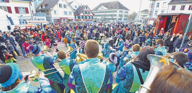Die Schlosshüüler aus Bürglen spielen nach dem Umzug auf der kleinen Konzertbühne am Marktplatz. Viele verkleidete Kinder und meist unverkleidete Erwachsene hören ihnen zu. (Bilder: Mario Testa)