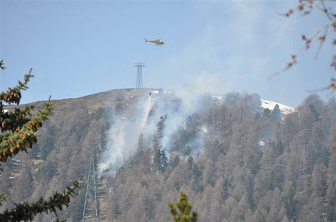 Mit Helikoptern werden die Flammen im schwer zugänglichen Gebiet in Celerina bekämpft. (Bild: Kapo GR)