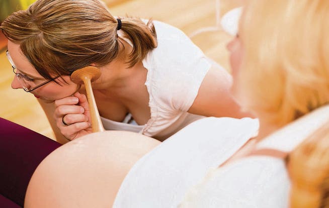 Eine Hebamme hört die Herztöne eines ungeborenen Kindes im Mutterbauch ab. (Bild: fotolia)