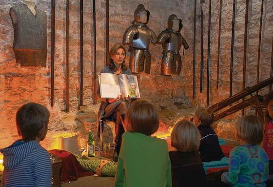 Im Waffensaal erzählt Adriana Exer den staunenden Kindern die Geschichte von Vincelot und dem Feuerdrachen. (Bild: Severin Schwendener)