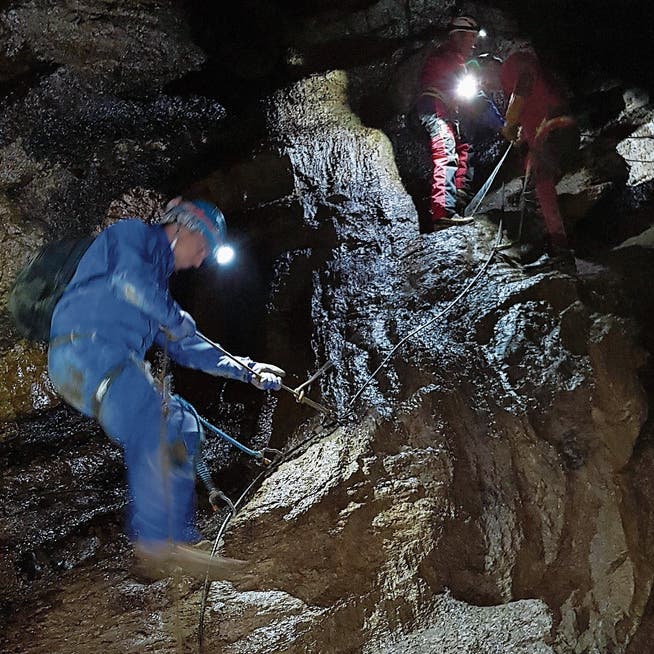 Mit Stirnlampen ausgerüstete Teilnehmer einer begleiteten Tour überwinden eine steile Passage in der Schrattenhöhle. (Bild: NeKO-Stiftung)