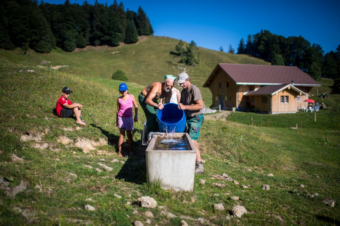 Köbi Alder und sein Sohn Ueli füllen einen versiegten Brunnen mit Wasser. (Bild: Benjamin Manser)