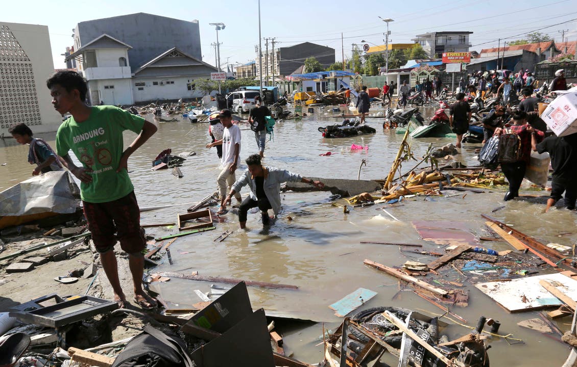 Einwohner betrachten das Ausmass der Zerstörung in Palu. (AP Photo/Tatan Syuflana)