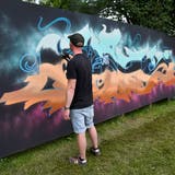 Ein Sprayer fertigt ein Kunstwerk an der Holzwand auf der Kreuzbleiche an. (Bilder: PD)