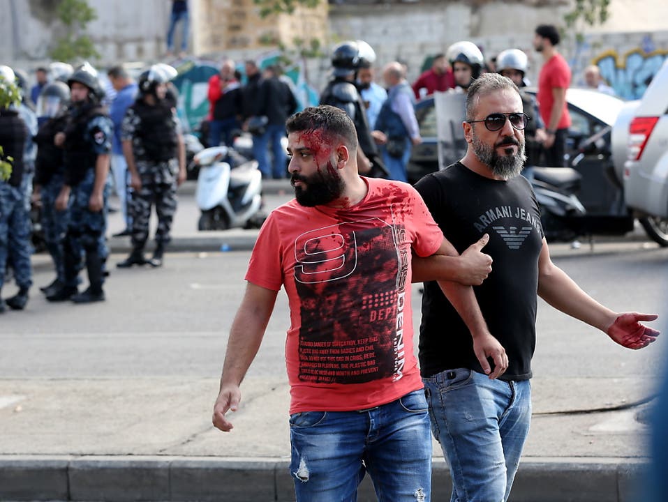 Die Hisbollah greift Protestler an: Ein Verletzter wird in Beirut nach einer Auseinandersetzung weggeführt. (Bild: KEYSTONE/EPA/NABIL MOUNZER)